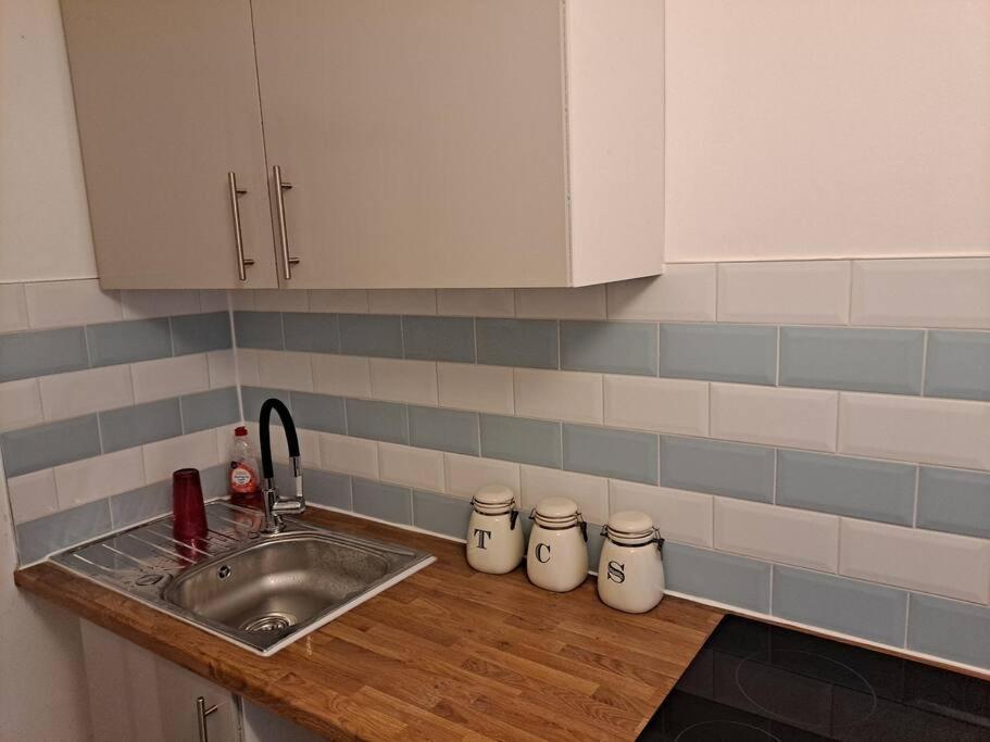 a kitchen counter with a sink and white cabinets at Two bedroom maisonette close toWarwick Uni in Canley