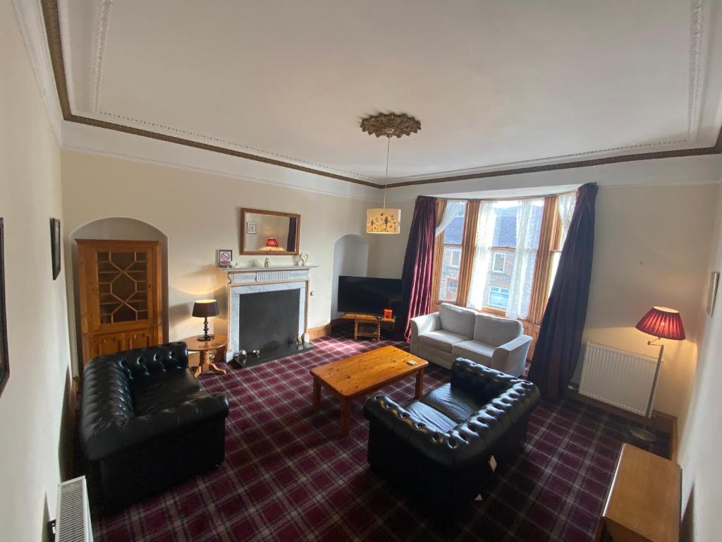 a living room with leather furniture and a fireplace at 92 High Street in Aberlour