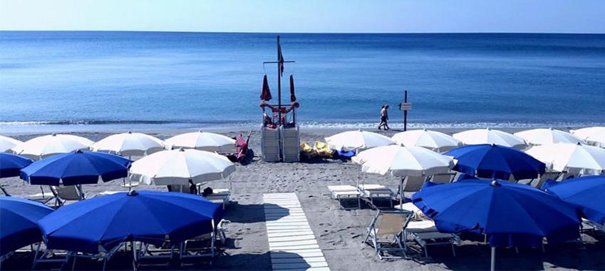 a group of blue and white umbrellas on a beach at Savona Casa Vacanze vicino Mare 3 minuti WIFI in Savona