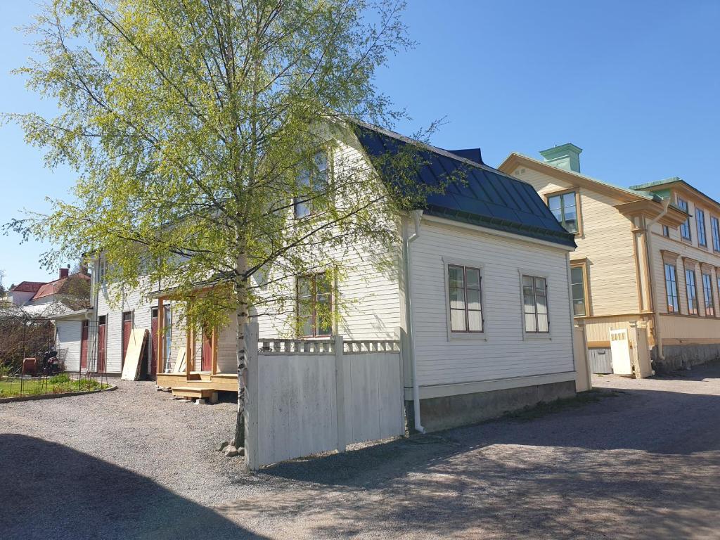 a white house with a fence and a tree at Välrenoverad fin lägenhet i charmigt område in Söderhamn