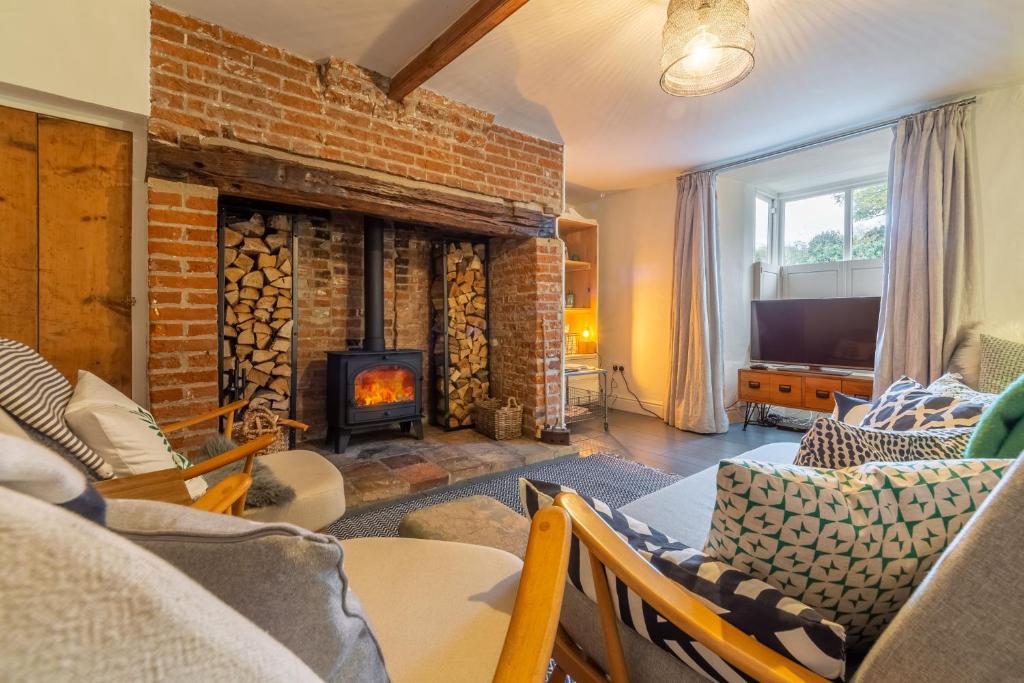 a living room with a brick fireplace and a tv at Willow Cottage in North Creake
