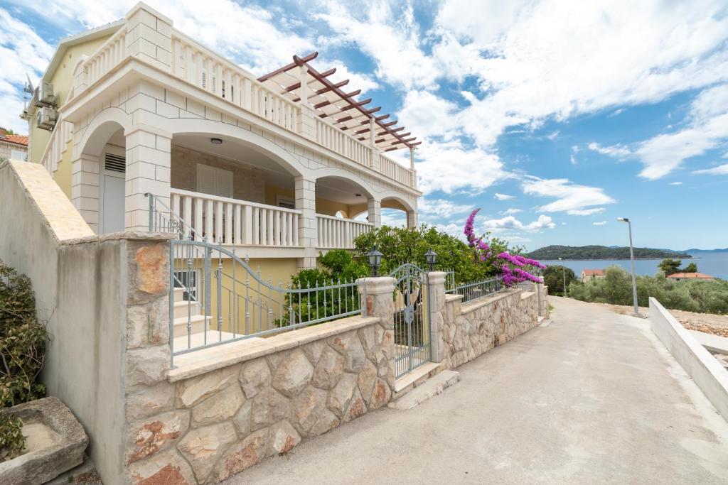 a large white house with a stone wall at Holiday house with a swimming pool Prizba, Korcula - 199 in Prizba