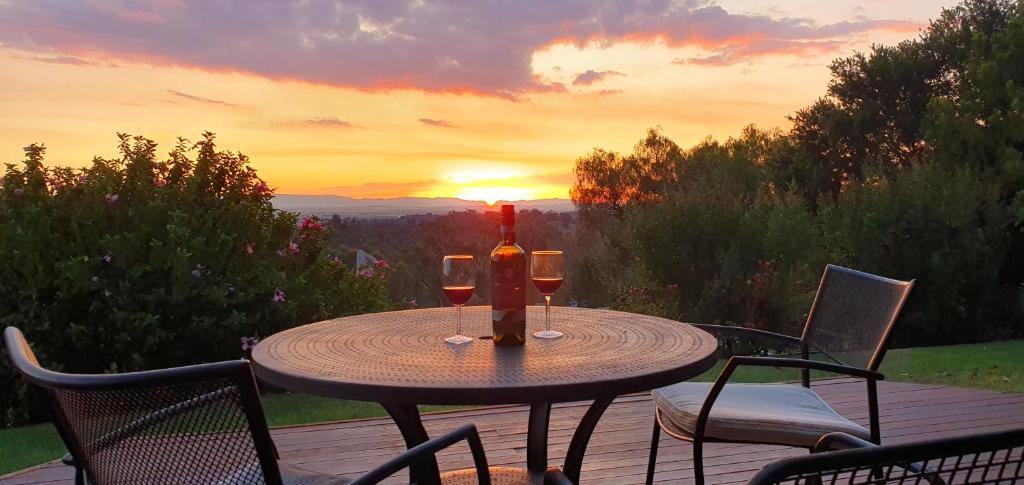 una mesa con copas de vino en una terraza con puesta de sol en Studio Daruka, en Tamworth