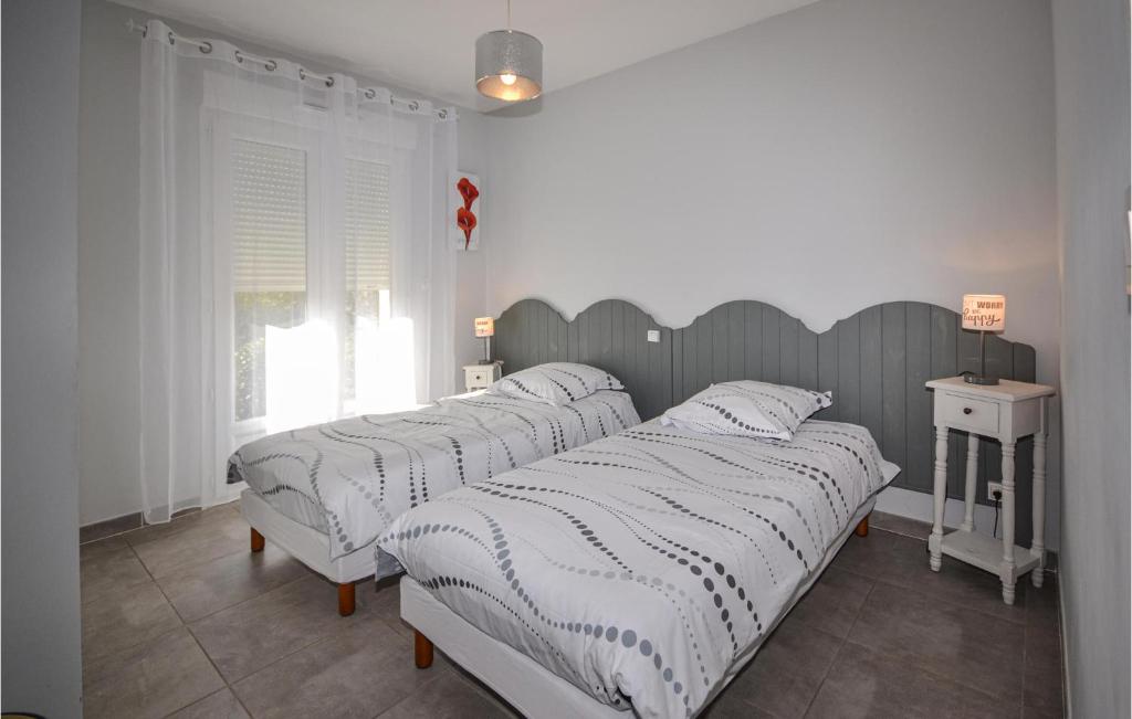 a bedroom with two beds and a table and a window at 2 Bedroom Amazing Home In Saint-ambroix in Saint-Ambroix