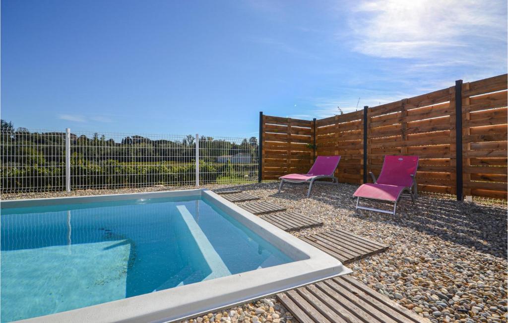 a swimming pool with two purple chairs next to a fence at 2 Bedroom Amazing Home In Saint-ambroix in Saint-Ambroix