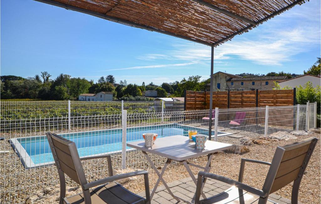 a patio with a table and chairs next to a swimming pool at 2 Bedroom Amazing Home In Saint-ambroix in Saint-Ambroix