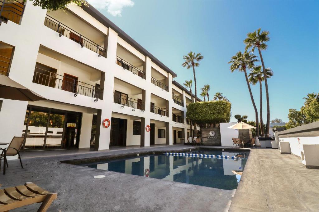 a hotel with a swimming pool in front of a building at Baja Inn Hoteles Rio in Tijuana