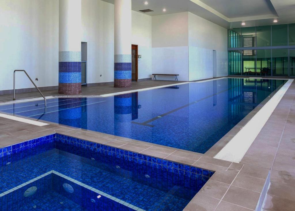 a large swimming pool with blue tiles in a building at Cozy Chic Haven: Modern Comfort in Gold Coast