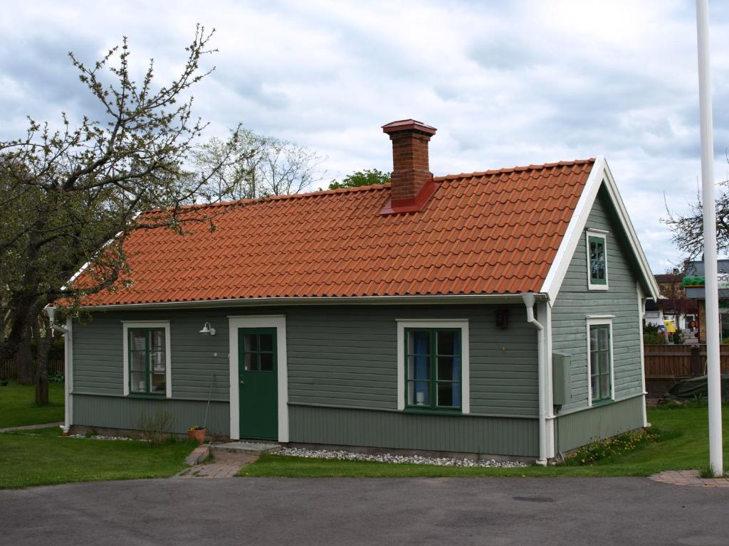 Skänninge的住宿－斯卡寧住宿加早餐旅館，一座带橙色屋顶的灰色小房子