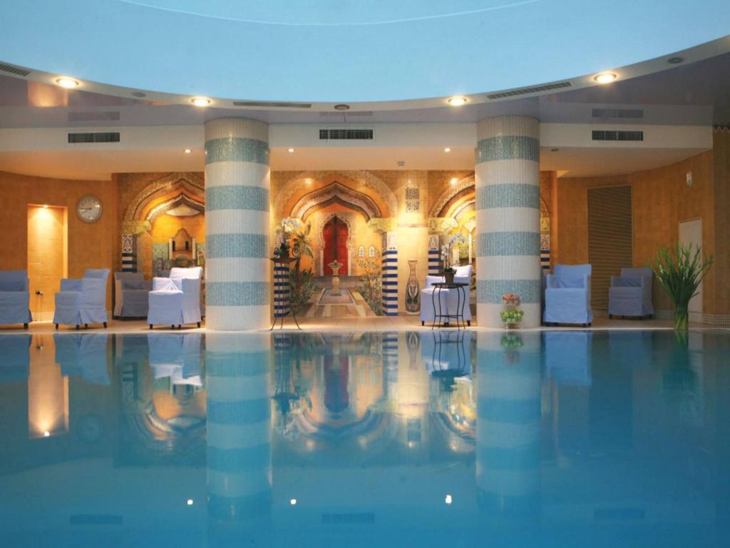 a large swimming pool in a hotel with columns at Oasis Spa Club Dead Sea Hotel - 18 Plus in Ein Bokek
