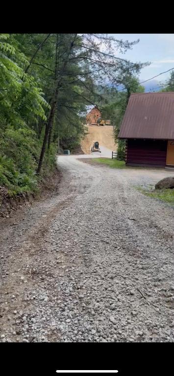 eine unbefestigte Straße mit einem Gebäude und einer Scheune in der Unterkunft Dollywood! Brand new Dancing Bear 3-Bear Tracks in Pigeon Forge