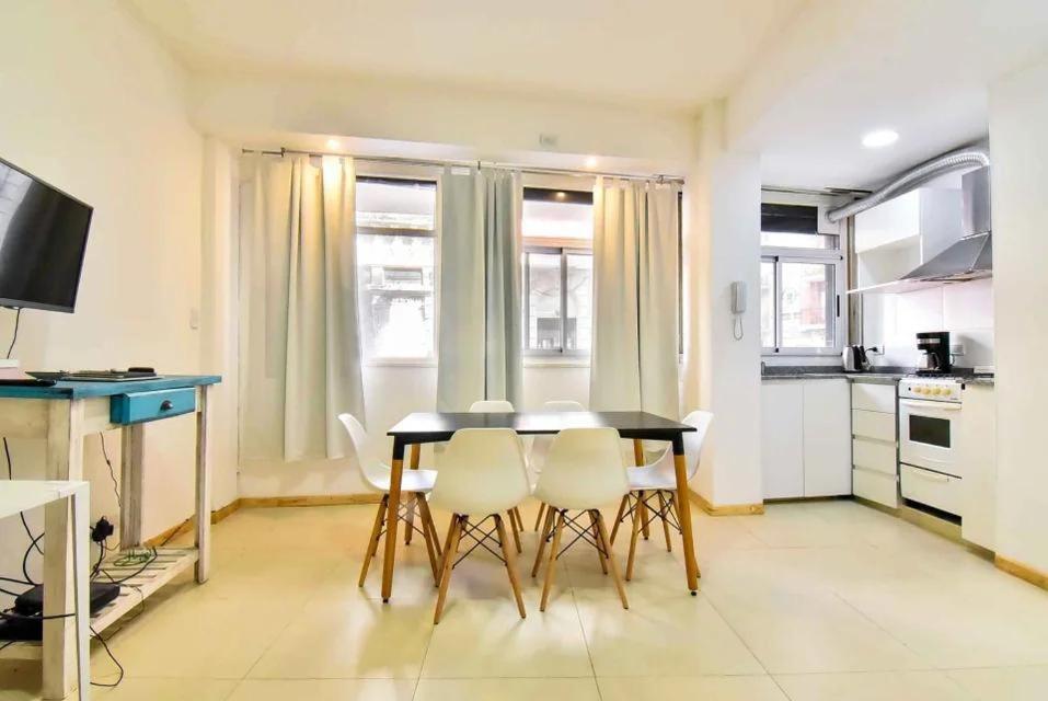 cocina con mesa negra y sillas blancas en Confortable departamento amoblado de 2 ambientes en RECOLETA con patio en Buenos Aires