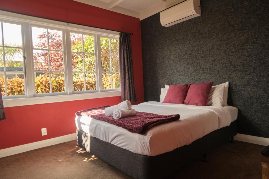 a bedroom with a bed with red walls and windows at Victorian Designs - Spacious Home in Rotorua Central in Rotorua