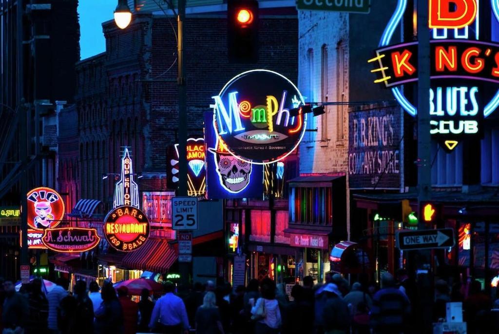una trafficata strada cittadina di notte con insegne al neon di Beale Streeters Delight a Memphis