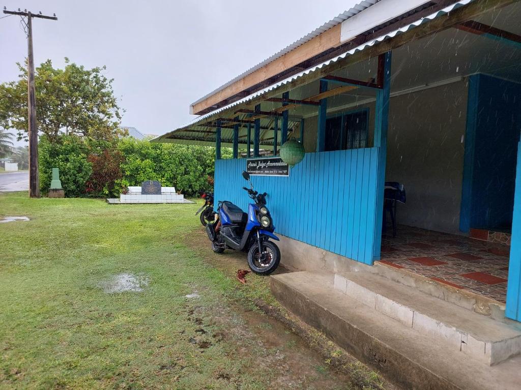 a scooter parked outside of a blue building at Aitutaki Budget Accommodation in Amuri
