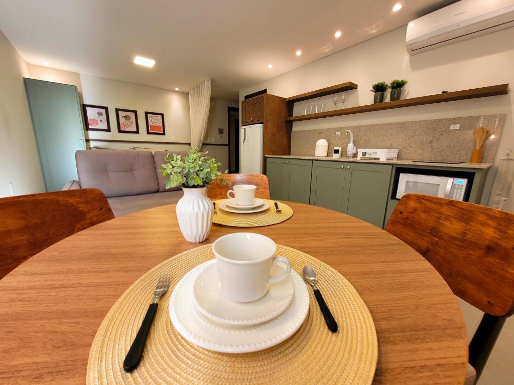 una mesa de madera con platos y tazas en la cocina en Residence Farol - Loft 204 en Laguna