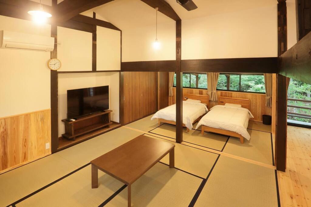 Habitación grande con 2 camas y chimenea. en 【コテージくぎの】大谷川沿いの露天風呂があるコテージ, en Minami Aso