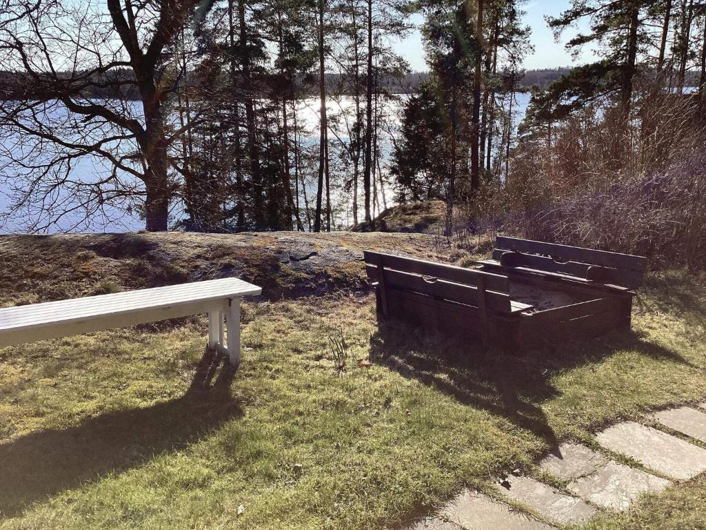 un banco sentado en el césped junto a un cuerpo de agua en Holiday home Vingåker III, en Vingåker
