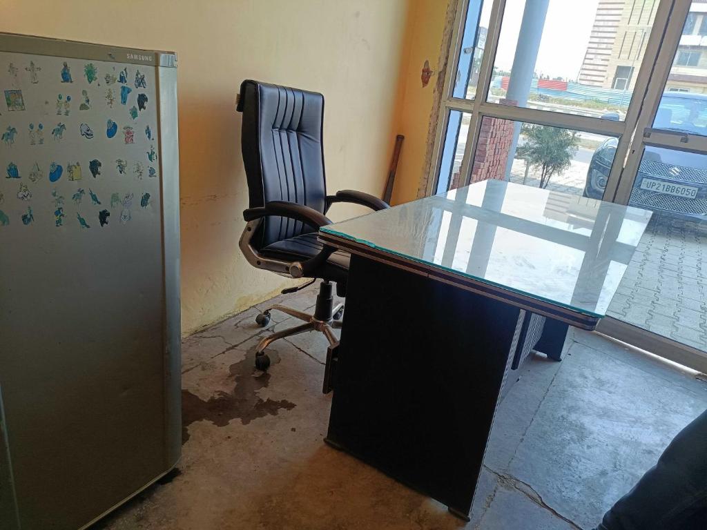 una oficina con escritorio de cristal y silla en SPOT ON Hotel Golden Gajraula, en Gajraula