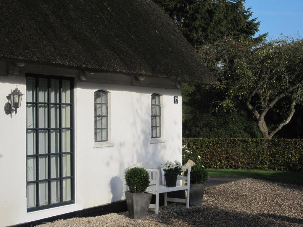 a small white cottage with a thatched roof at Tåsinge B&B in Svendborg