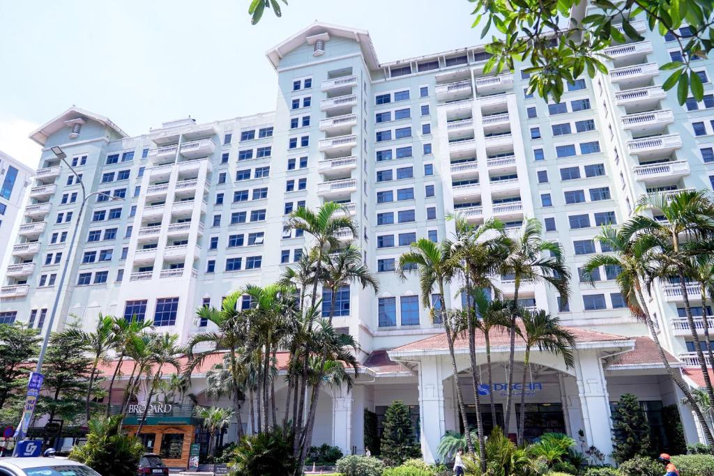 a large white building with palm trees in front of it at Daeha Serviced Apartment in Hanoi