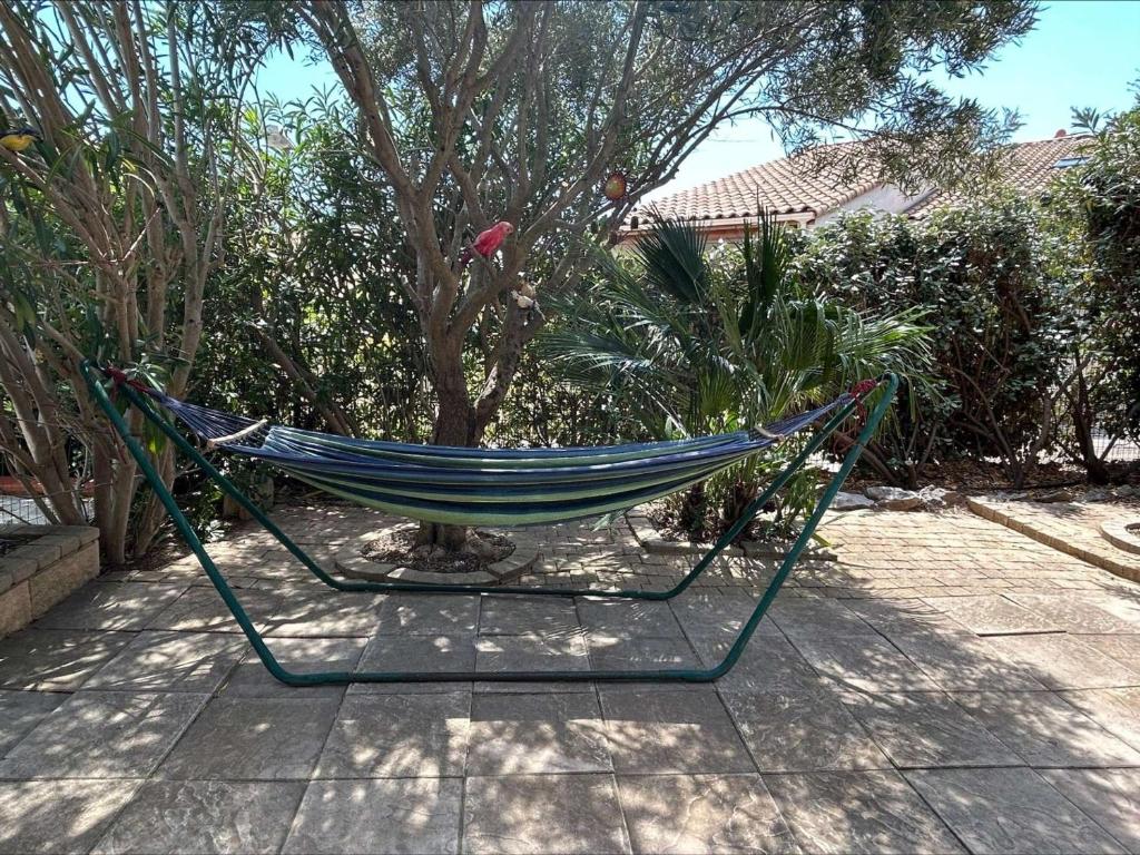 un hamac assis devant un arbre dans l'établissement Maison 3 pièces mezzanine, 7 couchages, piscine, proche plage à Saint Pierre la Mer - FR-1-229D-121, à Fleury