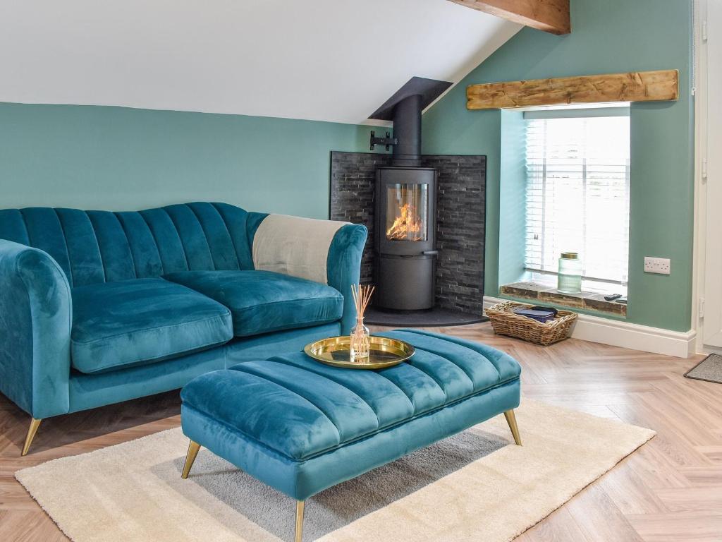 a living room with a blue couch and a fireplace at Barn Owls Nest-uk39432 in Dronfield