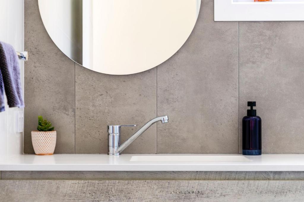 bagno con lavandino e grande specchio di Taylors Beach Cottage a Taylors Beach