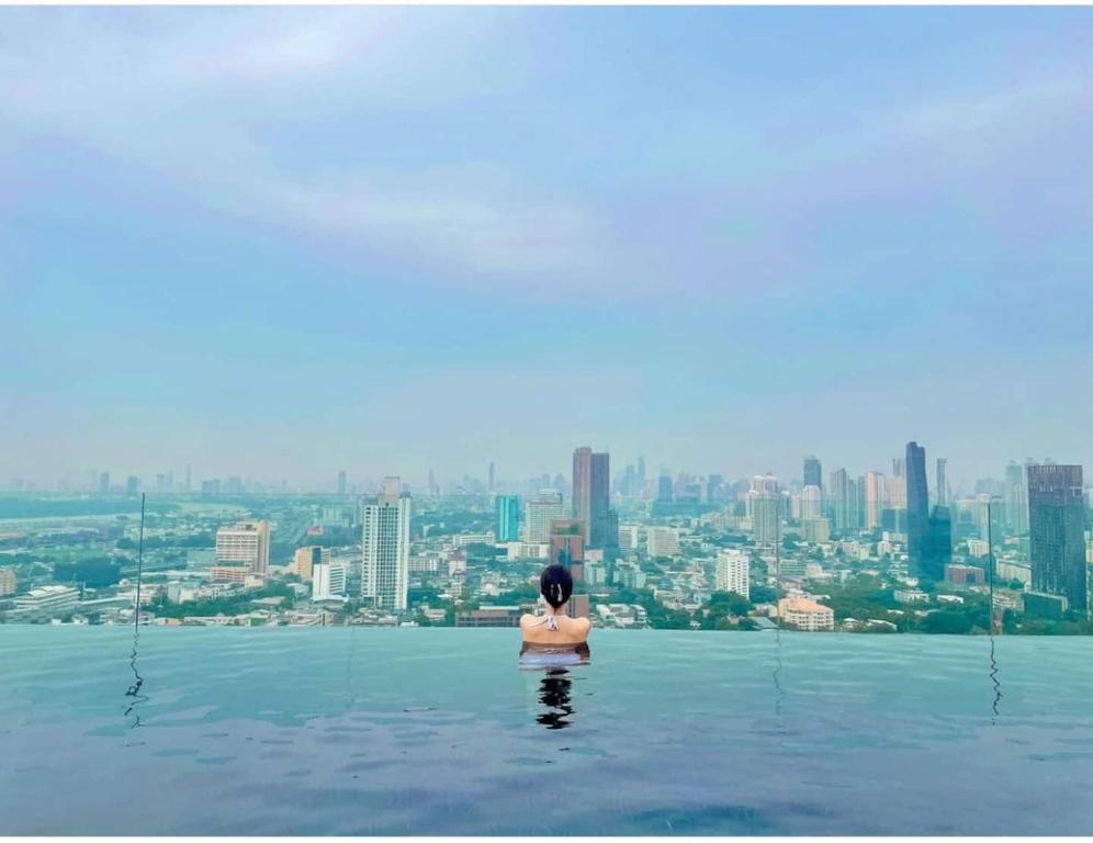 a woman standing in the water at the edge of the skyraper at 2 Bedroom Luxury Apartment 3 min walk from BTS Ekkamai in Bangkok