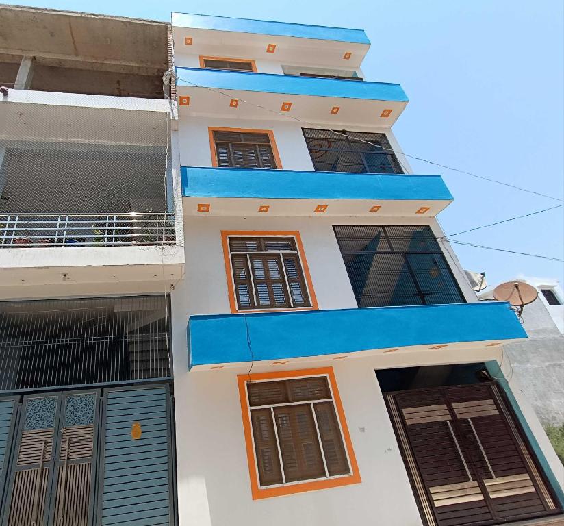 a white building with blue windows and a balcony at OYO HOME Satvik Homestay in Ayodhya
