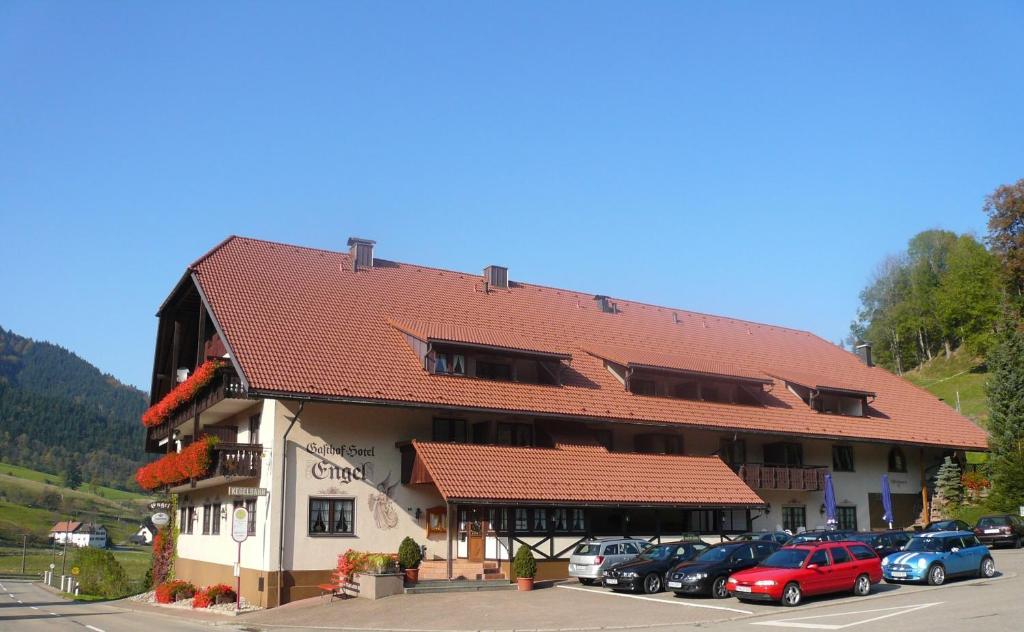 un grand bâtiment avec des voitures garées dans un parking dans l'établissement Gasthof Hotel Engel, à Simonswald