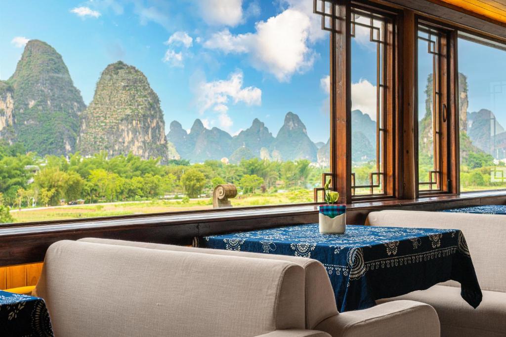 a room with a table and chairs and a view of the mountains at Li River Gallery Lodge in Yangshuo