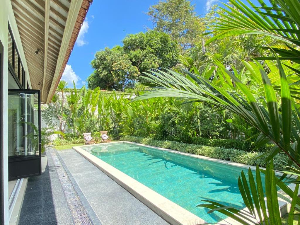 a swimming pool in a yard with palm trees at The Villas Umalas in Canggu