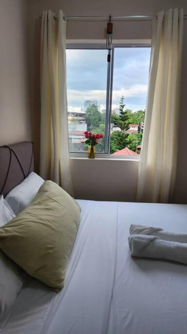 a bedroom with a bed with a window and a pillow at Denise's Midtown Condo in Davao City