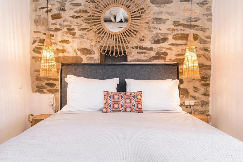 Schlafzimmer mit einem Bett, einem Spiegel und Lampen in der Unterkunft Heritage Home with Terrace in the trendy port of Naousa in Naoussa