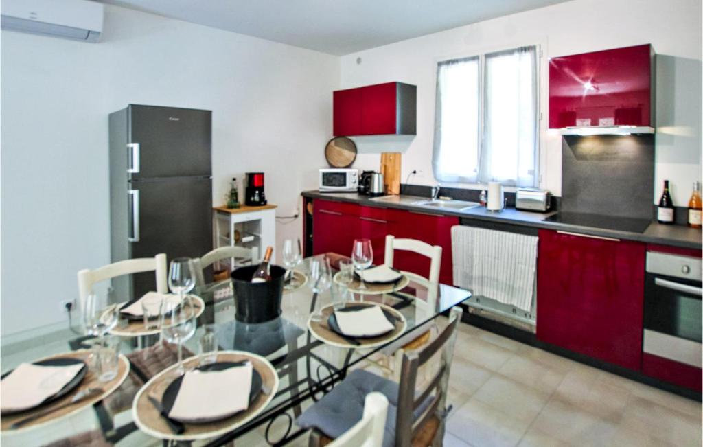 a kitchen with a glass table and red cabinets at Cozy Home In Merindol With Outdoor Swimming Pool in Mérindol