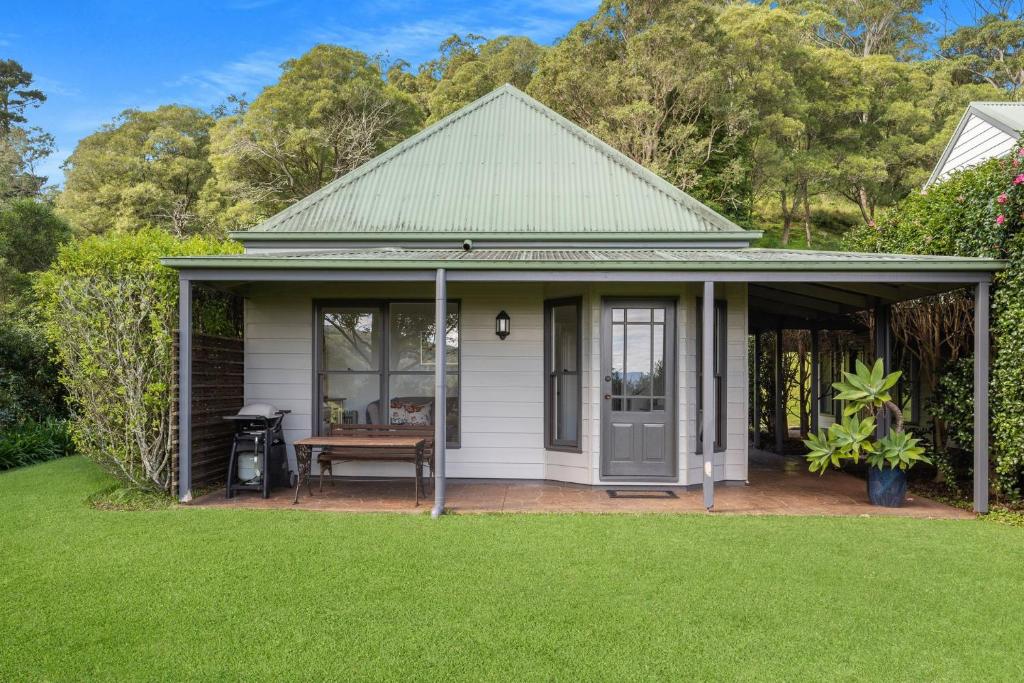 a white house with a porch with a picnic table at Watta Cottage in Wattamolla