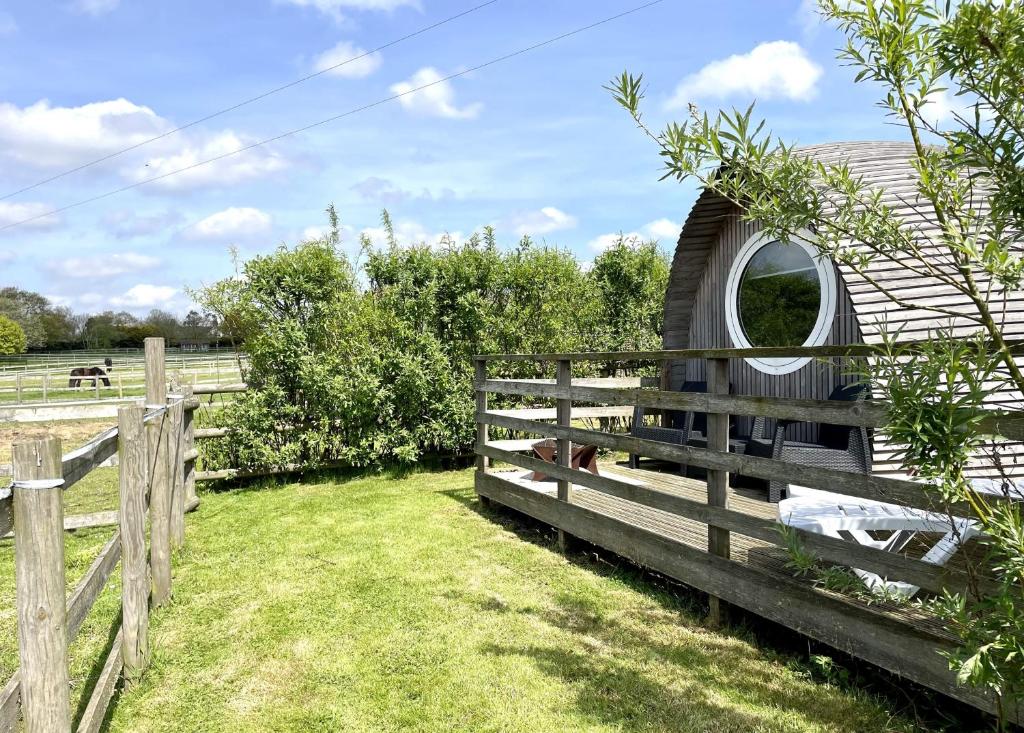 a barn with a fence and a circular window at Armadilla 2 at Lee Wick Farm Cottages & Glamping in Clacton-on-Sea