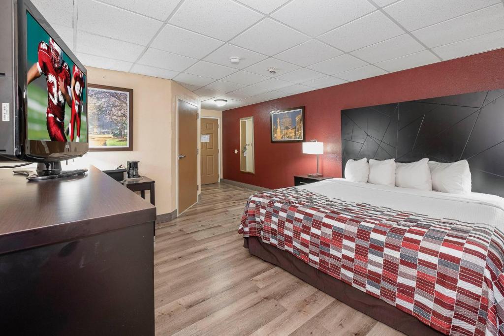 a hotel room with a bed and a flat screen tv at Red Roof Inn & Suites Macon in Macon