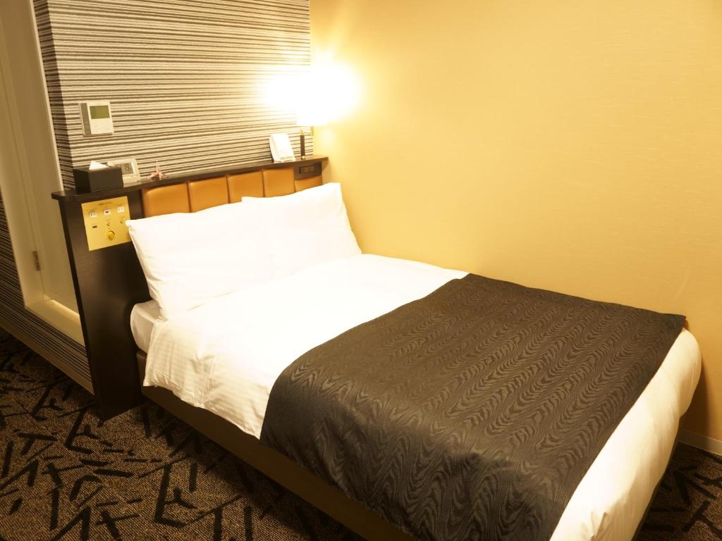 Postel nebo postele na pokoji v ubytování APA Hotel Saitama Yatsuka Ekimae