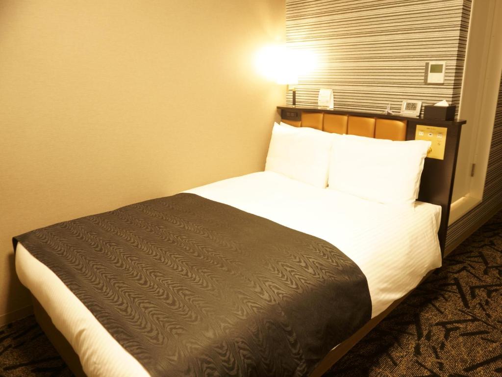 Postel nebo postele na pokoji v ubytování APA Hotel Saitama Yatsuka Ekimae