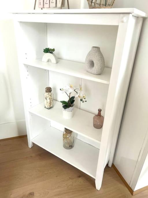 a white book shelf with flowers and vases on it at F2 Bohémien au centre ville in Corbeil-Essonnes