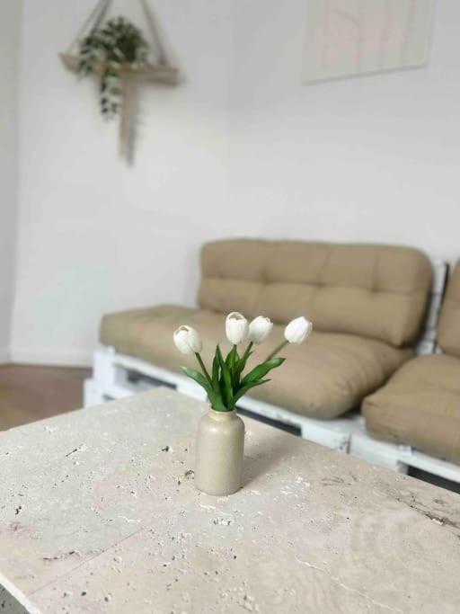 a vase with white flowers on a table in a living room at F2 Bohémien au centre ville in Corbeil-Essonnes