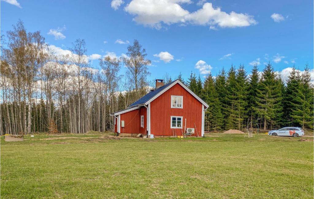 un granero rojo en un campo con un coche en Nice Home In Tjurstorp With Kitchen, 