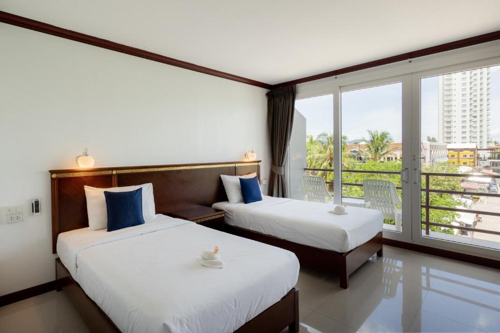 2 bedden in een hotelkamer met een balkon bij Hotel De Karon in Karon Beach