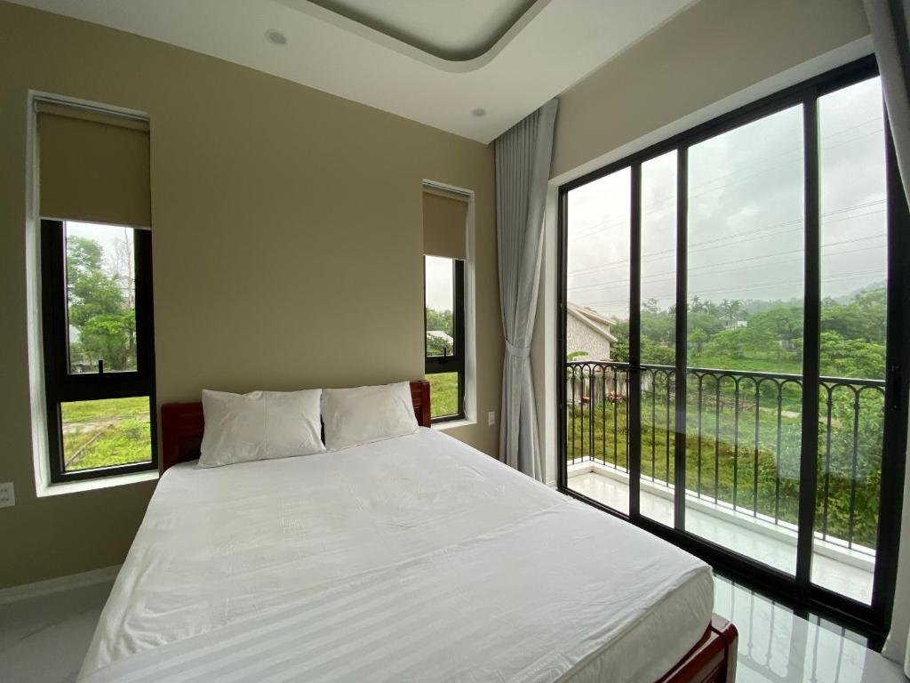 1 dormitorio con 1 cama y 2 ventanas grandes en Lá Homestay en Ấp Tư Tây