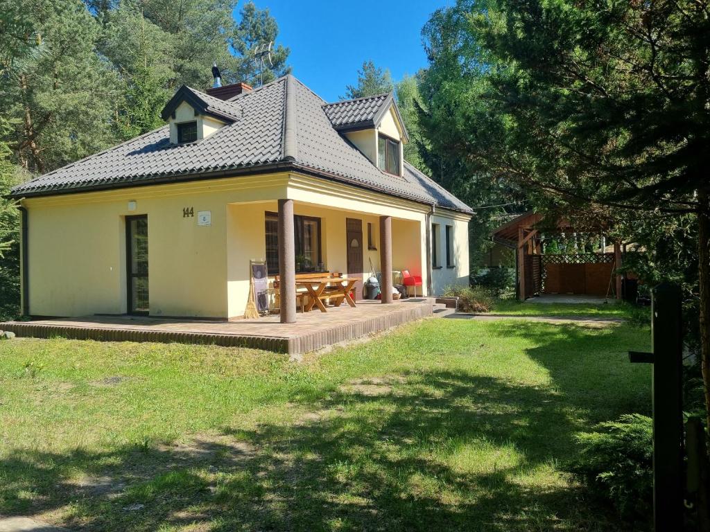 una pequeña casa amarilla con patio y patio en Domek nad rzeką, en Joniec