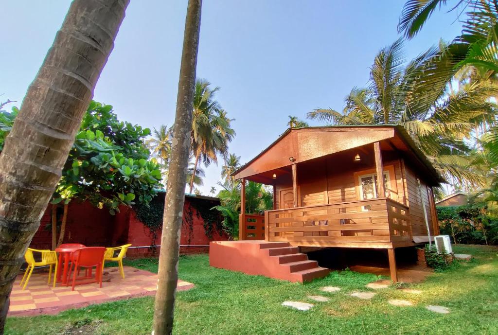 een klein houten huis met een tafel en stoelen bij Tranquil Beach Resort in Harihareshwar