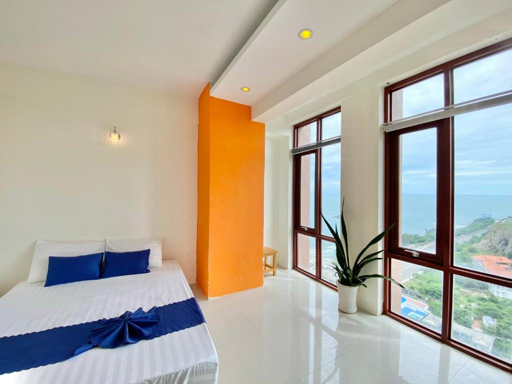 a bedroom with a bed with blue pillows and windows at ZoZo house - Homestay Bai Sau in Vung Tau