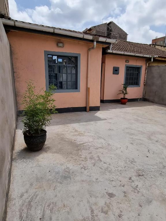 a house with two potted plants in front of it at Lux Suites Donholm Family Bungalow in Nairobi